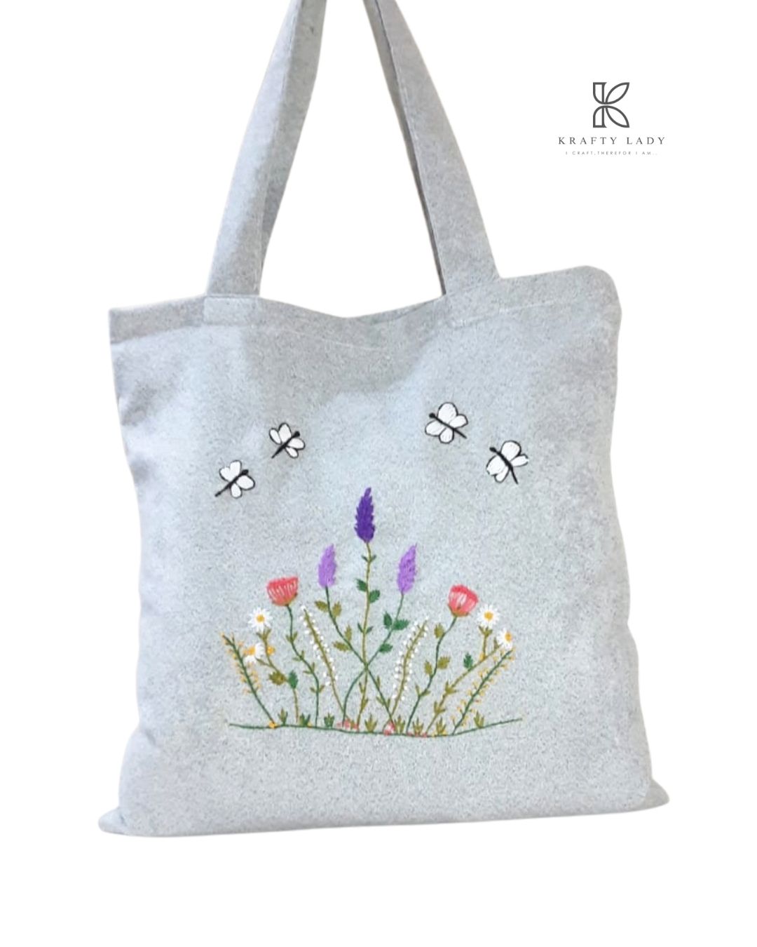 Gray tote bag with floral and insect embroidery on a white background